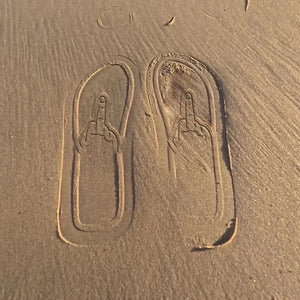 Middle finger footprints pressed into beach sand
